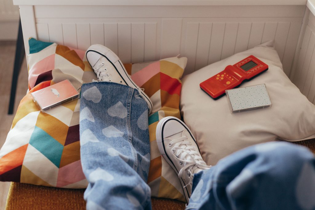 Teen’s sneakers | teenage and mood swings katy, tx | teen counselor | online therapy for teens | Katy, Texas | Cinco Ranch | Nottingham | Katy High School | Cane Island A teen's sneakers rest on patterned pillows surrounded by cassette tapes and a small gadget. Can teenage mood swings show up even during quiet, relaxed moments at home? Teen anxiety counseling in Katy, TX offers support for navigating these ups and downs.