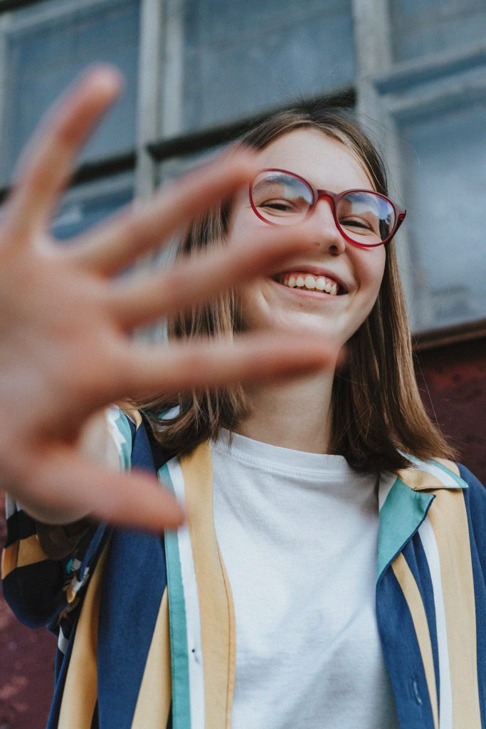 Teenage girl | teenage mood swings katy, tx | teen therapy| teen counseling | Katy, Texas | Grand Lakes | Governor's Place | Rhodes Stadium A teenage girl in glasses smiles and holds up her hand close to the camera. Is moodiness in teenagers something every parent will face at some point? A teen anxiety counseling in Katy, TX approach can help families understand these shifts.